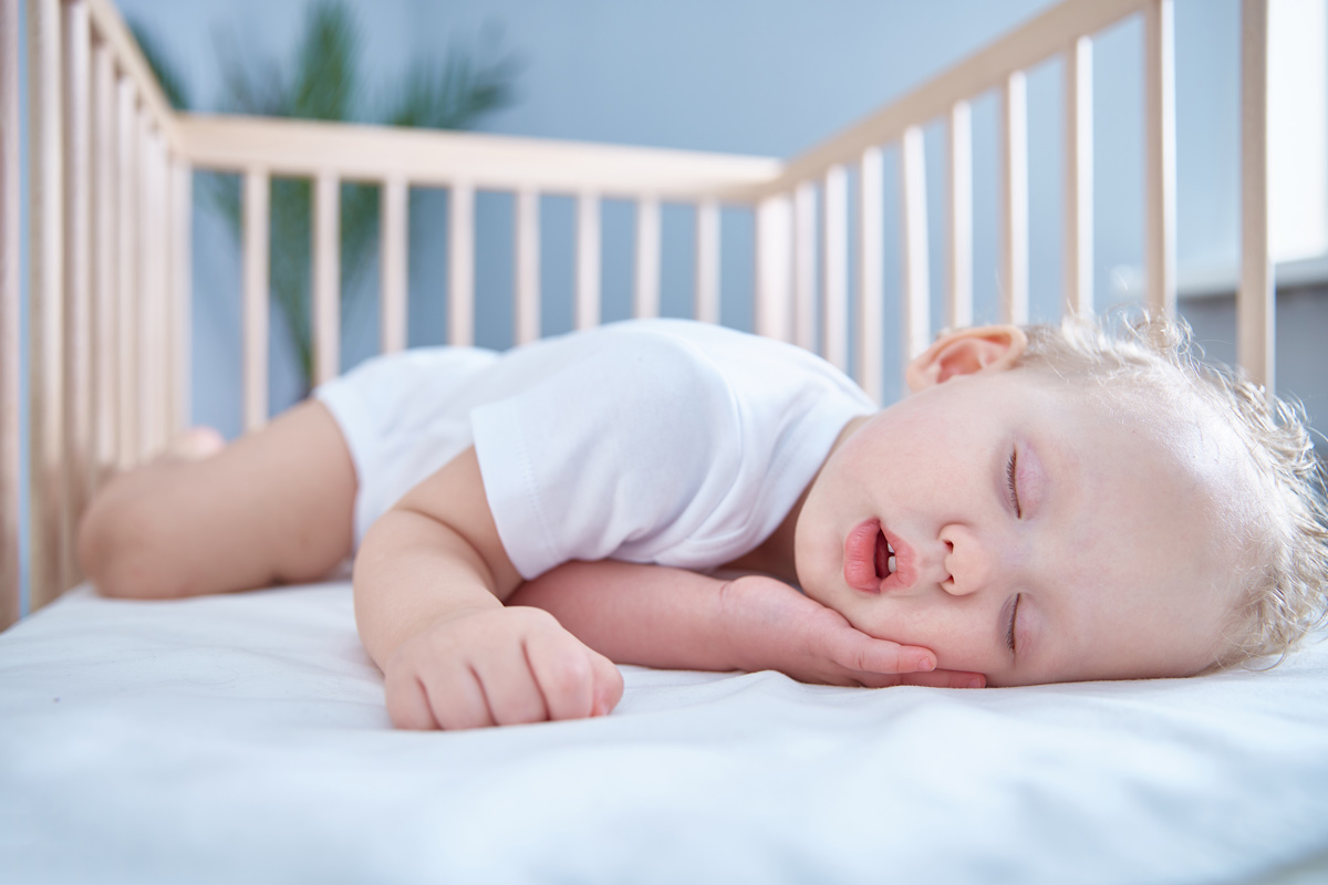 Bebé a dormir tranquilamente de lado, a posição que ajuda a prevenir a paralisia do sono
