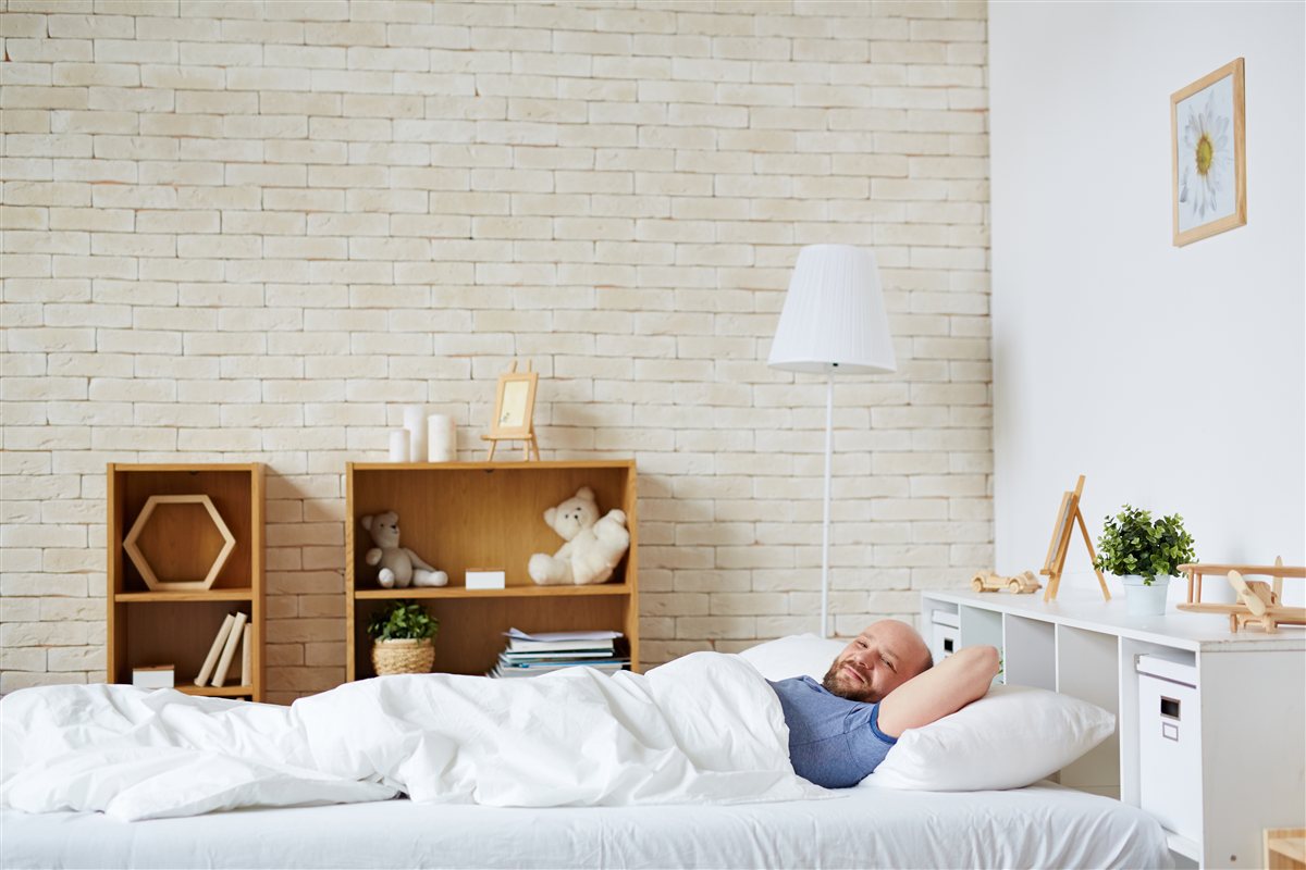 Homem a acordar relaxado e descansado na cama, sorridente, depois de finalmente ter um diagnóstico